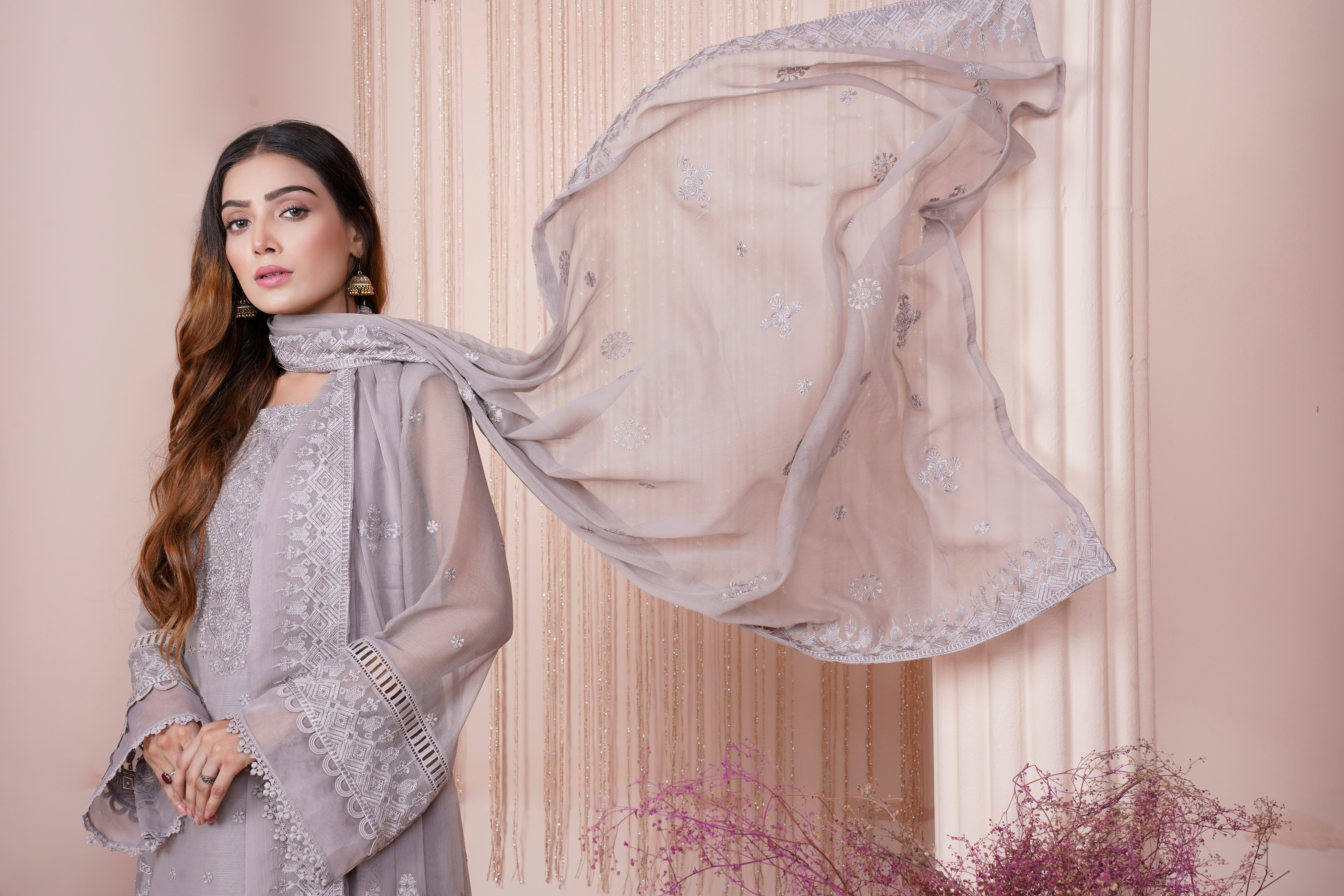 Elegant model in flowing grey embroidered outfit with intricate lacework